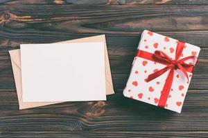 Envelope Mail with Red Heart and gift box over Dark Wooden Background. Valentine Day Card, Love or Wedding Greeting Concept photo