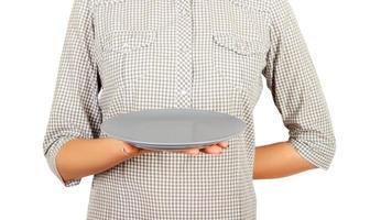 la camarera sostiene un plato mate redondo vacío con una mano. plantilla de vista en perspectiva para su diseño. aislado sobre fondo blanco foto