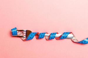 Top view of obesity concept with fork wrapped in measuring tape on blue background photo