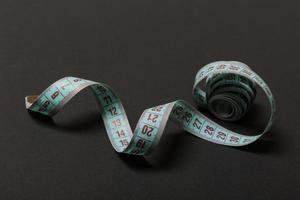 Perspective view of curled measure tape on black background. Keeping fit concept photo