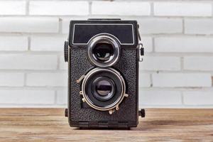 cámara antigua retocando vintage en mesa de madera. cámara retro con dos lentes foto
