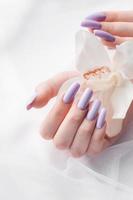 Girl's hands with delicate purple manicure and orchid flowers photo