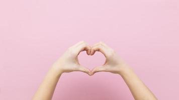 banner mujer joven tomados de la mano en forma de corazón sobre fondo rosa. foto