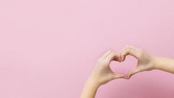 banner mujer joven tomados de la mano en forma de corazón sobre fondo rosa. foto
