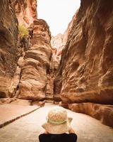 Tourist in Petra take photograph of The Siq, the narrow slot-canyon that serves as the entrance passage to the hidden city of Petra. Sightseeing destination of Jordan