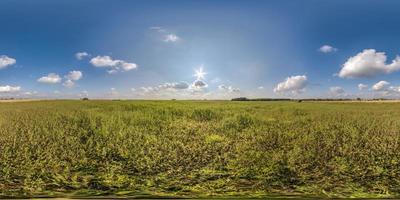 vista panorámica completa de 360 hdri entre el campo agrícola con sol y nubes en el cielo nublado en proyección esférica equirectangular, lista para usar como reemplazo del cielo en panoramas de drones o contenido vr foto