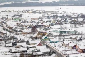 aerial panoramic winter view of village with houses, barns and gravel road with snow photo