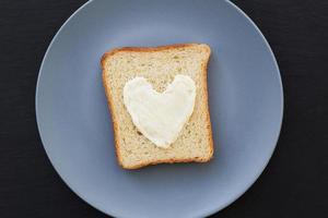 sándwich para el desayuno en forma de corazón con queso en un plato azul y fondo negro foto