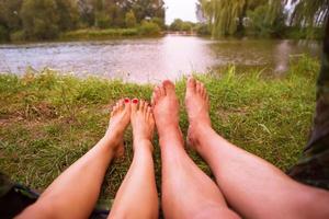 una pequeña tienda de campaña en el lago, una noche de alojamiento y los pies de una pareja joven foto