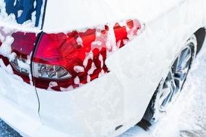 lavado de manos con agua a alta presión en un lavado de autos afuera. el coche está lleno de espuma. el concepto de lavado de manos, autoservicio. foto