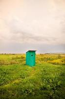 wooden toilet with a carved window in the shape of a heart, an open field photo