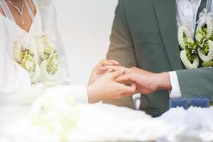 la novia lleva un anillo de bodas en el dedo anular izquierdo del novio el día de su boda foto