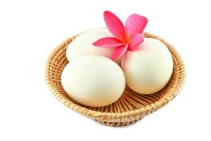 huevos de pato blanco en cesta y flor rosa aislado sobre fondo blanco huevo salado foto