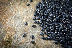 Pile of Black bean grain seeds on rustic wood background photo