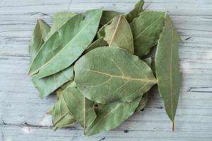 Dried whole bay leaves on cutting board, Laurus nobilis photo