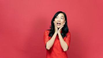 Young woman wearing traditional cheongsam qipao dress posing wow action isolated on red background. Happy Chinese new year photo