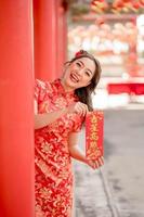 Happy Chinese new year. Beautiful lady wearing traditional cheongsam qipao dress holding blessing fortune card in Chinese Buddhist temple. Chinese text means blessed by a lucky star. Emotion Smile photo