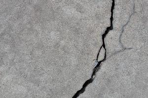 Concrete background with rough deep crack. Gray back. photo