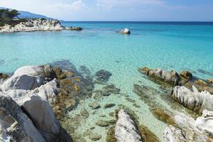 seascape with clear turquoise water among rocks and stones, in the distance you can see the horizon line photo