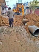 Excavator dig the trenches at a construction site. Trench for laying external sewer pipes. Sewage drainage system in Pakistan photo