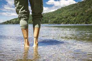 Woman feet in water with her legs tattooed with 2 hearts. photo