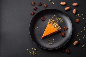 Beautiful tasty pumpkin pie with slices on a black ceramic plate photo