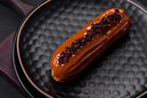 delicioso eclair fresco con crema de chocolate en un plato de cerámica negra foto