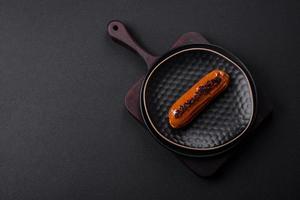 Delicious fresh eclair with chocolate cream on a black ceramic plate photo