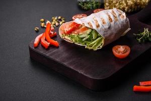 Delicious fresh shawarma with tomatoes, peppers, cucumber on a dark concrete background photo