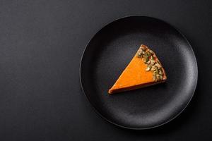 Beautiful tasty pumpkin pie with slices on a black ceramic plate photo
