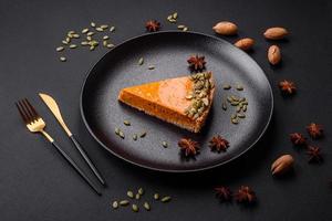 Beautiful tasty pumpkin pie with slices on a black ceramic plate photo