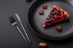 Delicious fresh pie with raspberries and other berries and cheese on a dark plate photo