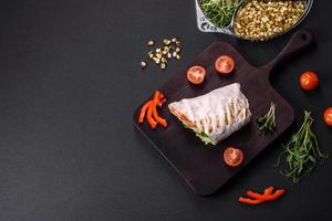 Delicious fresh shawarma with tomatoes, peppers, cucumber on a dark concrete background photo