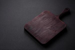 Empty brown wooden cutting board on dark concrete background photo