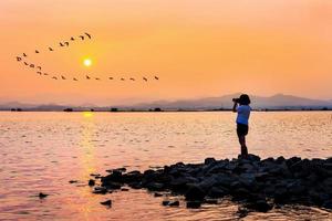 Young woman taking photos sunset on the waterfront