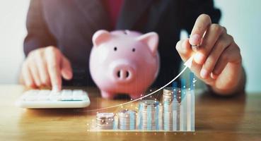 business woman holding pen pointing in graph with coins . concept saving money for future photo