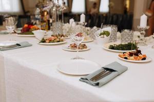 juego de vasos vacíos en el restaurante. boda, decoración, celebración, concepto de vacaciones - mesa romántica con mantel blanco, platos, vasos de cristal