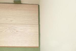 Installing wooden laminate or parquet floor in room over green base. assembling panels quickly and easily - affordable flooring. laying laminate flooring at home photo
