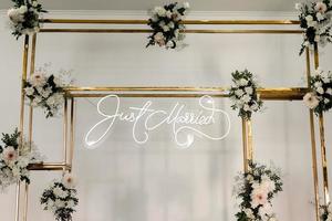 wedding rectangular metal gold arch design with fresh white flowers and greens on a white wall background. Festive decoration photo zone indoors