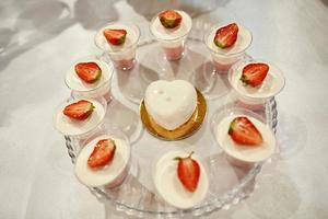 Wedding candy bar with pink and white deserts. Strawberry cupcakes, jelly and modern desserts. photo