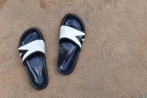 wet black flip flops on the sand ground photo