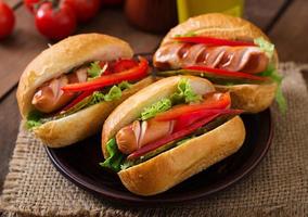 hot dog - sándwich con pepinillos, pimentón y lechuga sobre fondo de madera