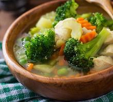 Chicken soup with broccoli, green peas, carrots and celery in  bowl on a wooden background in rustic style photo