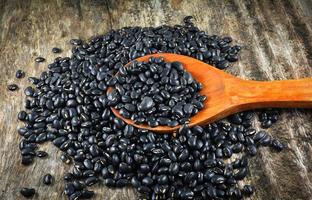 Black bean on wooden spoon on rustic wood background grain seeds photo