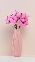 Pink ceramic vase with rose cotton bouquet on white table photo