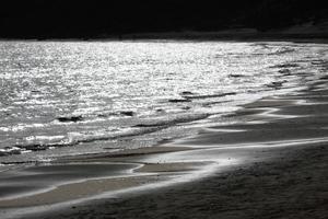 lonely beach with people strolling on the sand at the edge of the sea waves photo