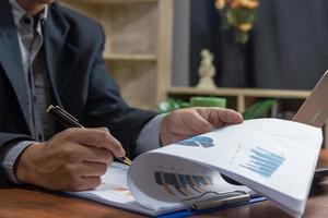 la persona de negocios lee el gráfico de estadísticas comerciales informa el documento de inversión de estrategia financiera y de marketing en el escritorio. foto