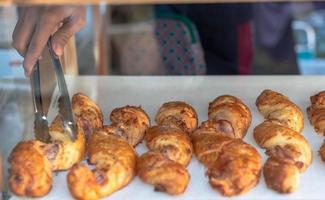 Female hand putting croissants on a wooden tray prepare for sell at the bakery shop. photo