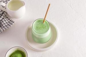 delicious healthy matcha latte tea in a glass of straw on a ceramic tray. white background. a healthy drink. Detox. photo