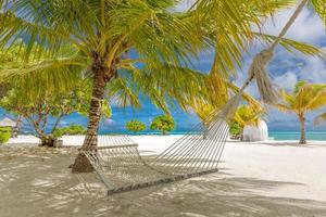 hermosa playa tropical de maldivas bajo un cielo nublado con columpios en cocoteros. concepto de vacaciones de lujo, luna de miel romántica y pancarta de escapada. árbol de coco, cielo azul, paisaje de arena blanca, paisaje marino foto
